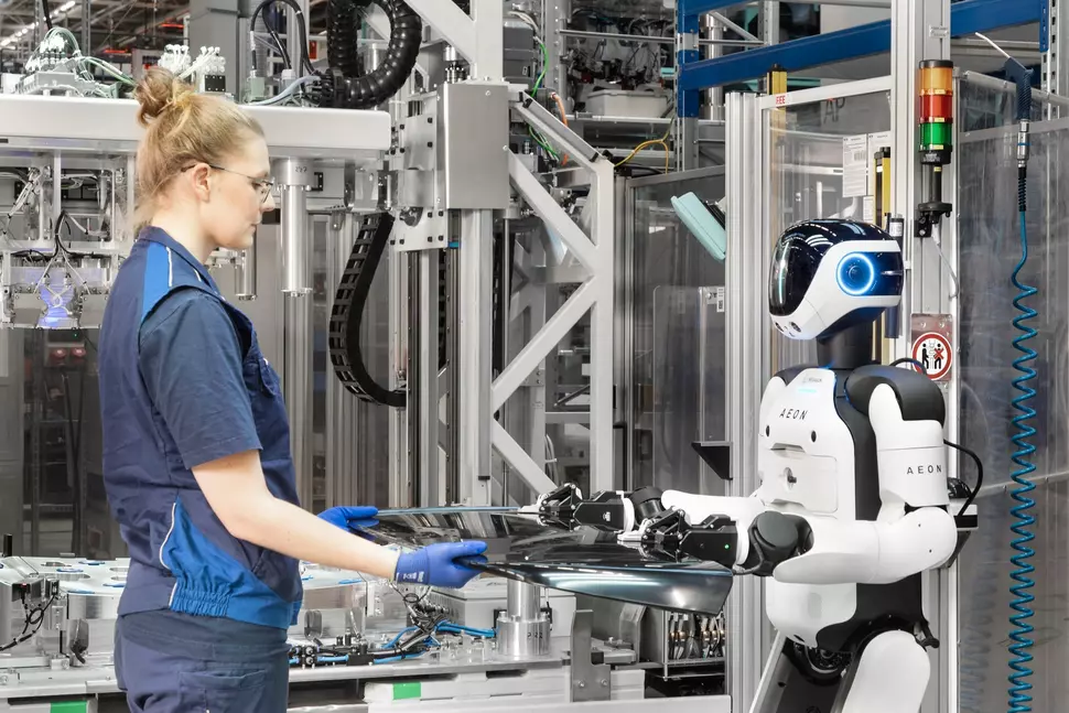 Weibliche Mitarbeiterin interagiert mit dem humanoiden Roboter in der Produktion im BMW-Werk Leipzig