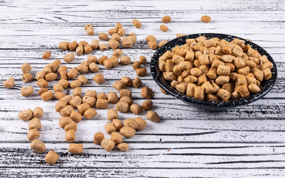 Pellets in einer Schüssel auf weißem Holzuntergrund