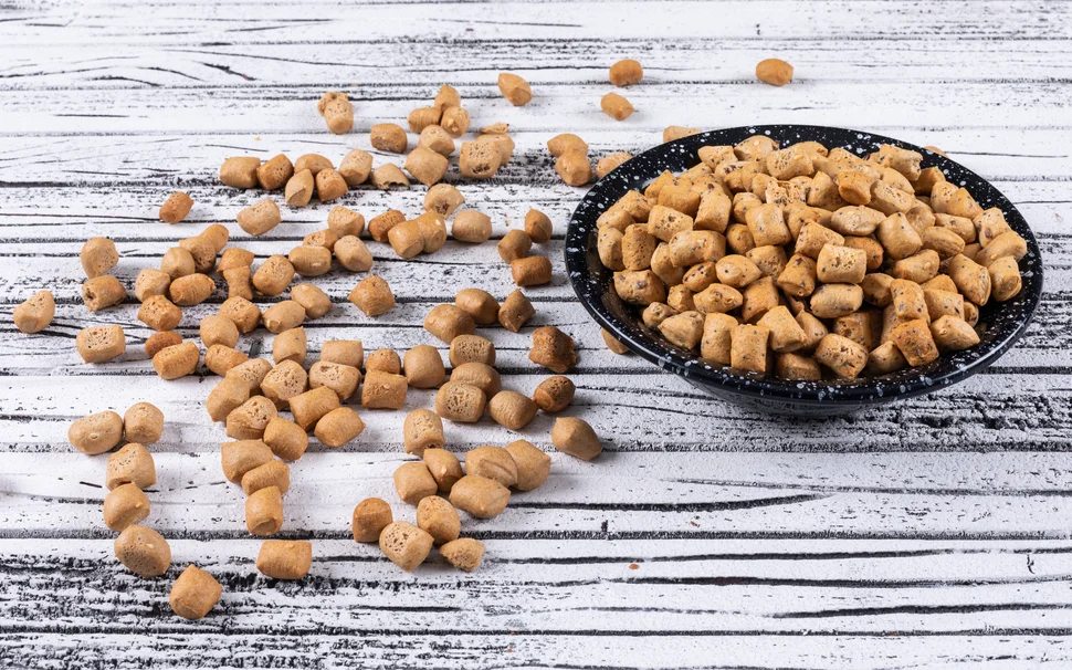 Pellets in einer Schüssel auf weißem Holzuntergrund